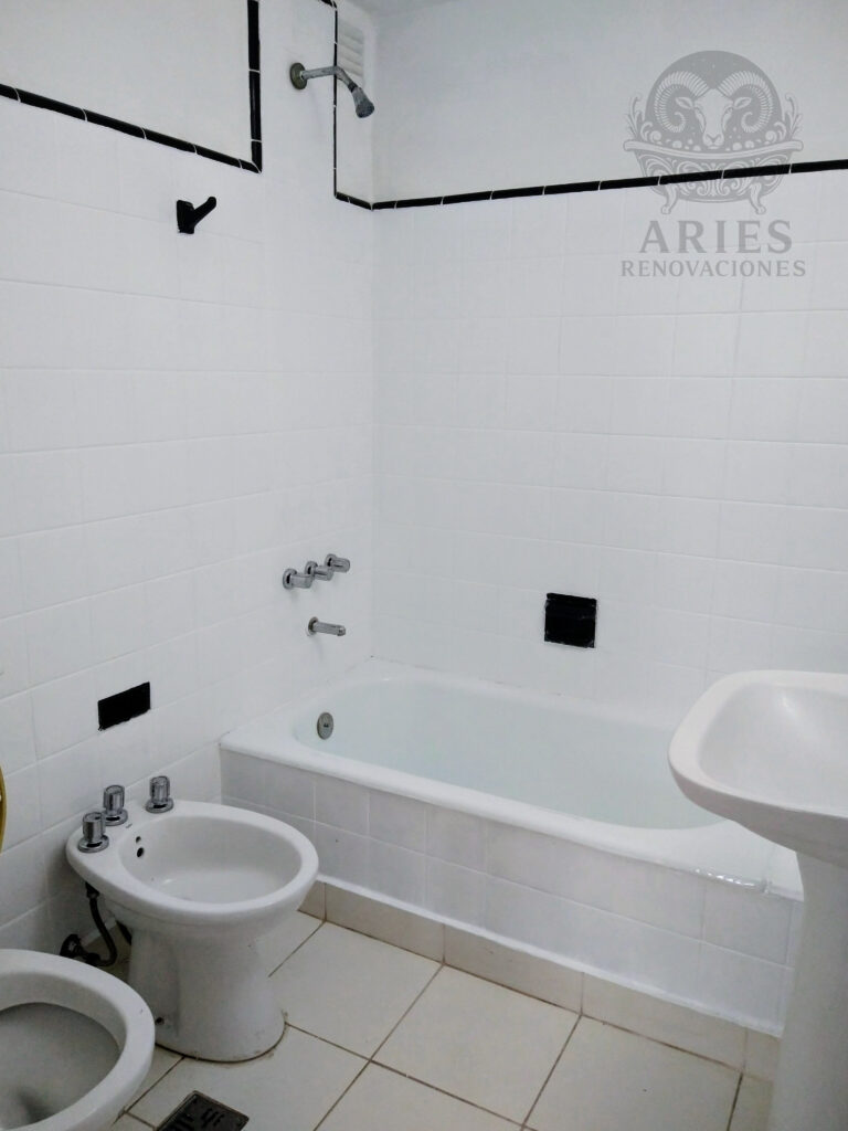 Baño renovado por Aries Renovaciones con bañera, revestimientos y sanitarios en blanco